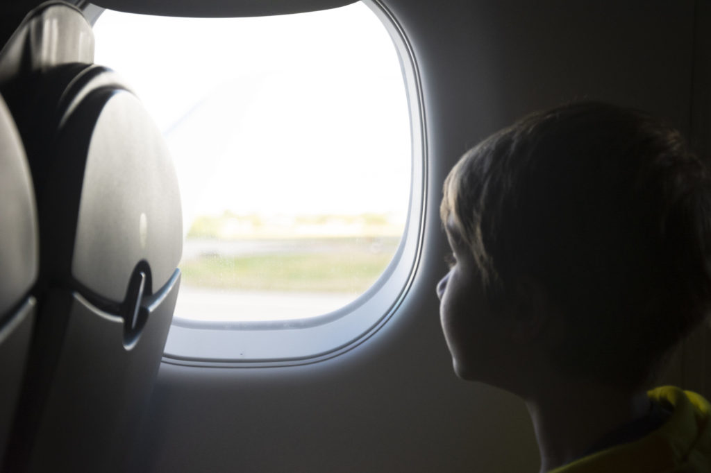 A child looks out the window while traveling on an airplane.